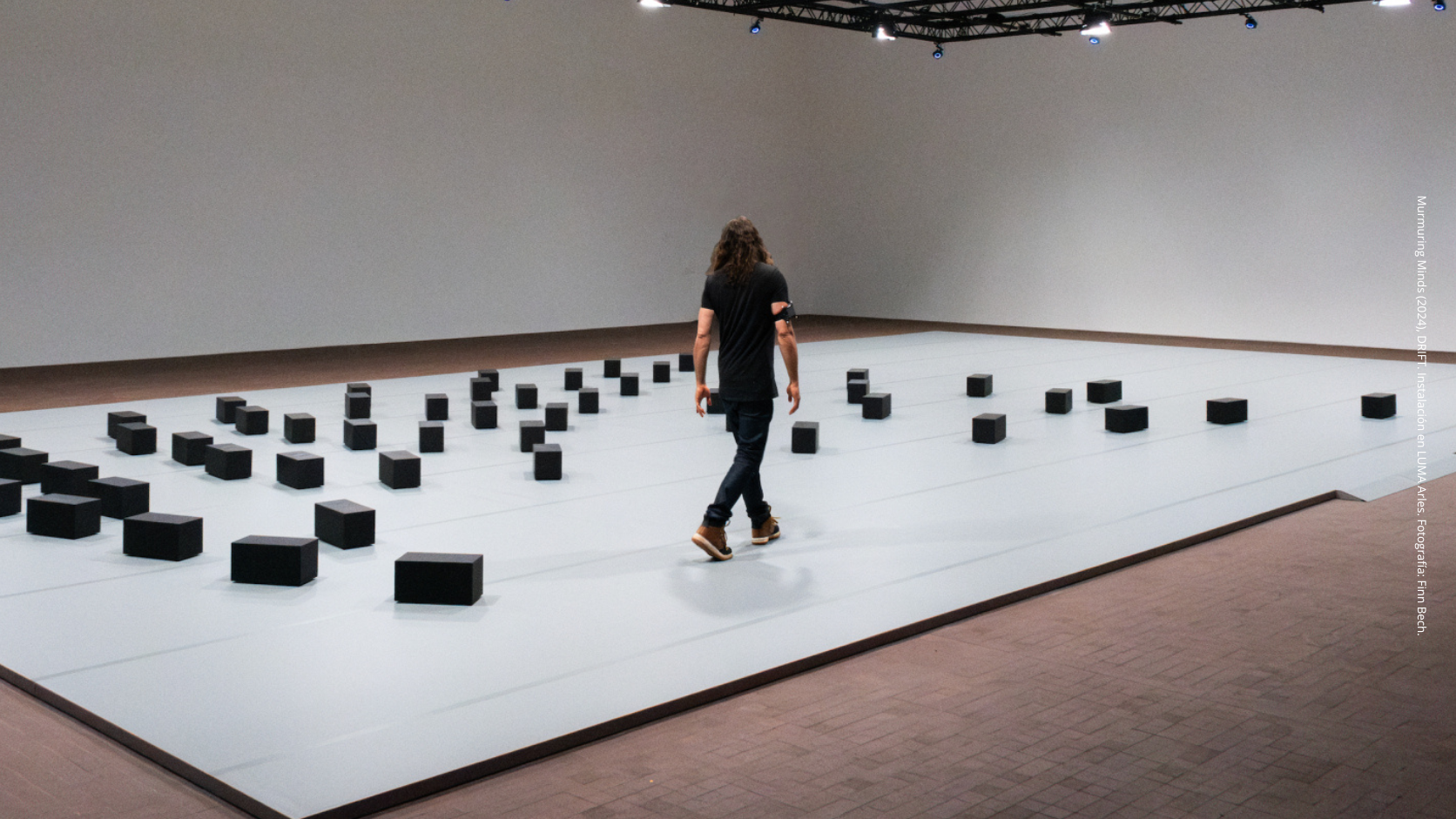 Instalación Murmuring Minds de DRIFT con bloques autónomos interactuando con una persona en LUMA Arles.